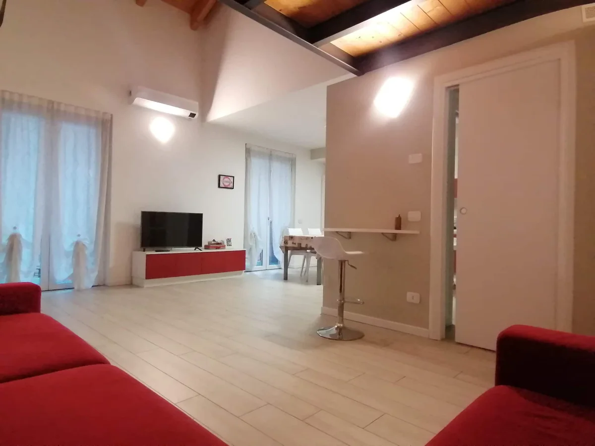 Il soggiorno con il divano rosso e la TV